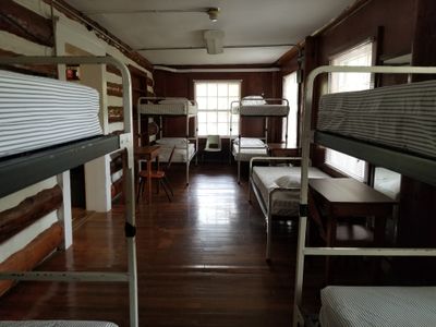 Inside a cabin at Jackson's Mill, four metal bunk beds with thick mattresses line the dark wooden walls.