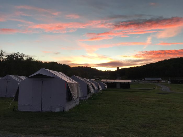 Sunrise at the SAS campsite: The sky is blue and gold, with pink and purple clouds, over rows of canvas tents.