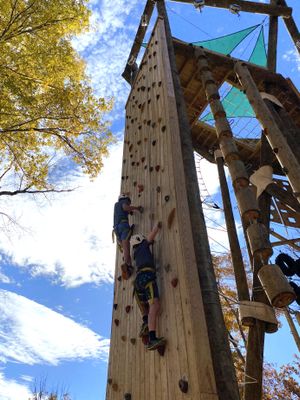 Two climbing students have almost reached the top of the Tango Tower rock wall.