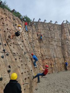 Students rock climb on a large, outdoor artificial climbing wall at the Summit.