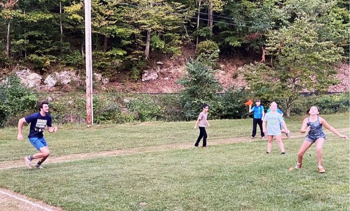 SAS staff and students appear to be playing a game in a grassy field, but no ball is visible.